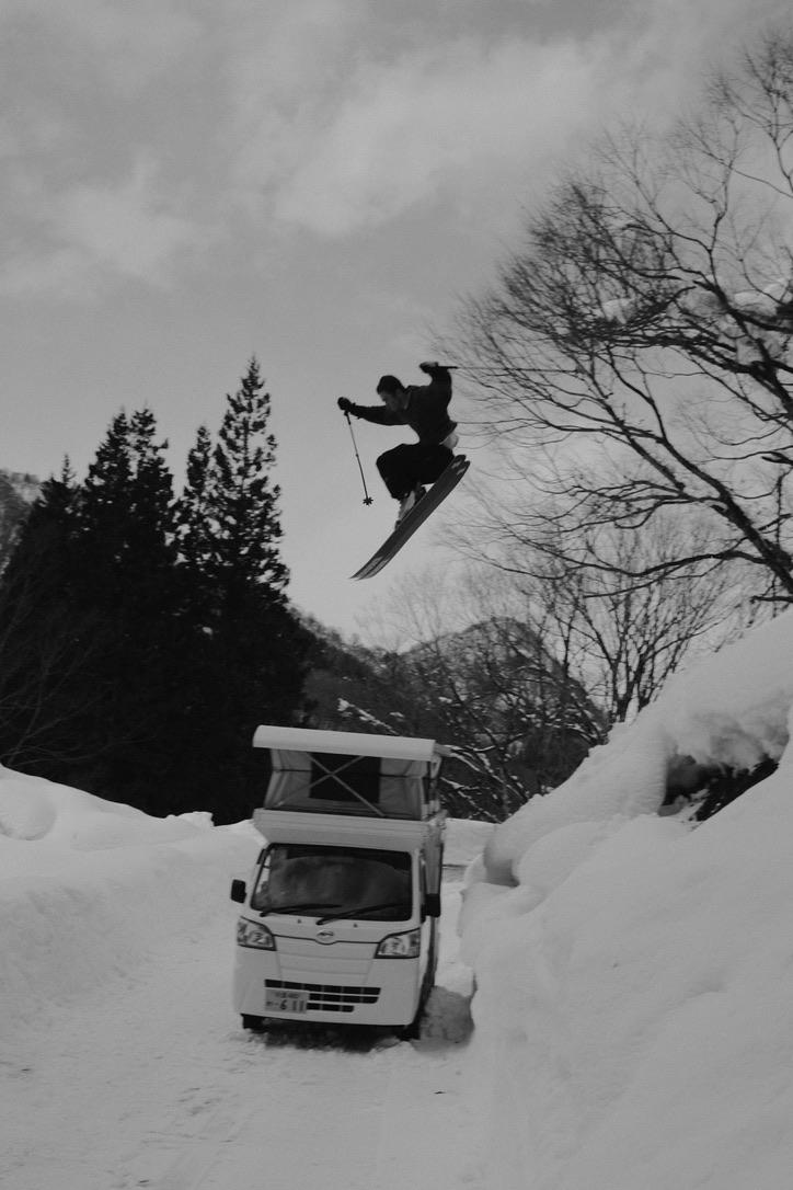 Skier jumping above a vehicle in deep snow
